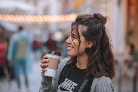 Lviv, Ukraine - July 17, 2019: young pretty woman at city street drinking coffee from disposable cup lifestyleのeditorial素材