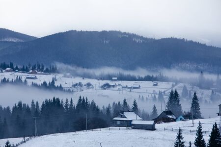 rural scene snowed village in mountains misty fogy morning landscapeの写真素材