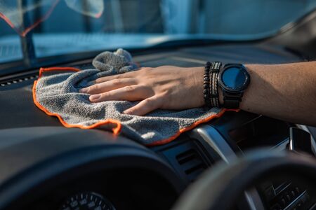man with dust cloth polishing car dashboard bracelet on handの写真素材