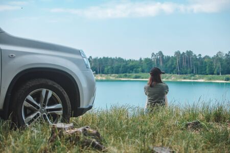 woman sitting on the edge enjoying view of the lake car travel concept