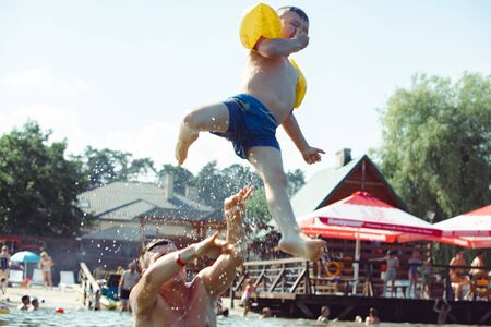 father throwing son in water having fun summer leisure activitiesの写真素材