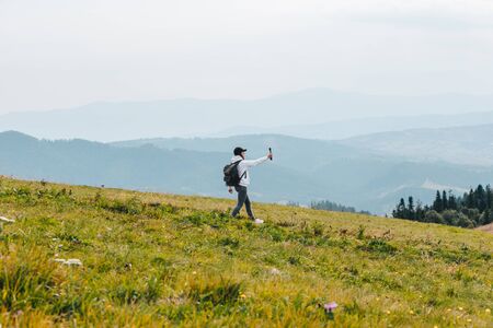 woman with backpack hiking in mountains shooting video on action camera autumn seasonの写真素材