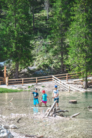 Braies, Italy - June 14, 2019: little kids playing in lake water. summer time. fun activitiesのeditorial素材