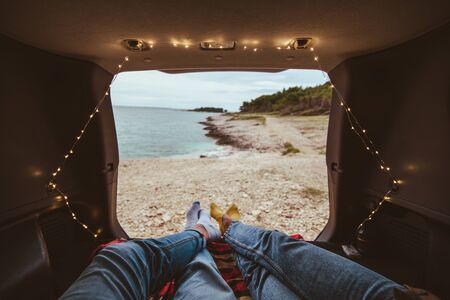 couple laying in the trunk of the car enjoying the view of sea beachの写真素材