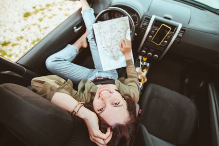 woman sitting in car checking map sea beach on background. summer vacation conceptの写真素材