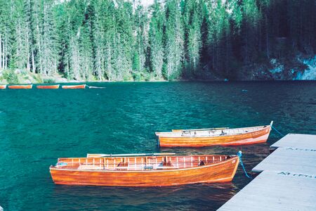 empty wooden boats near dock at mountain lake summer hiking placeの写真素材
