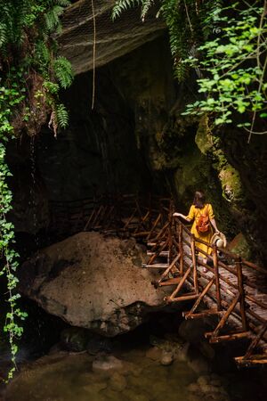 gorgeous woman in yellow sundress looking at caves with river creek. travel landmark. summer timeの写真素材