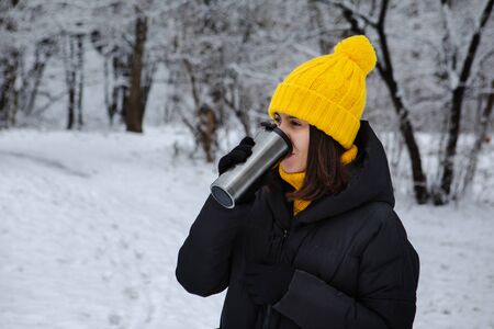 woman in winter outfit drinking warm up drink from refillable mug copy spaceの写真素材