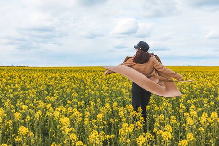 young pretty smiling woman walking in yellow rapeseed field. copy spaceの写真素材