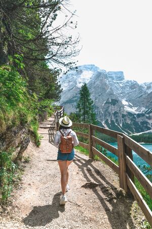 hiker woman with backpack walking by footpath trail around lake in mountains. copy spaceの写真素材