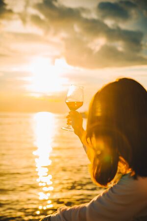 woman drink wine at sea beach looking on sunset. summer vacation.の写真素材
