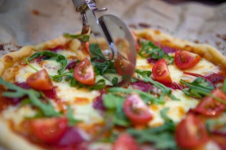 woman hand slicing pizza for pieces. close upの写真素材