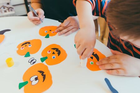 young mother with toddler son making craft pumpkins for halloween holiday family timeの写真素材