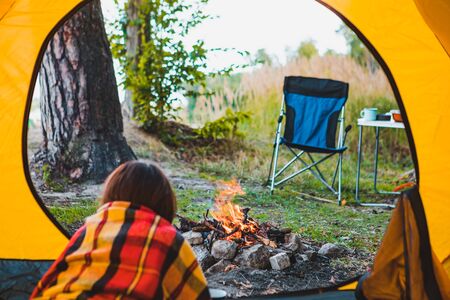 woman laying in yellow tent looking at bonfire camping conceptの写真素材