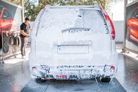 strong man washing car at self carwash outdoors summer timeの写真素材