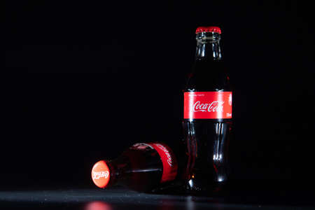 Lviv, Ukraine - May 21, 2020: two glass bottle of coca cola at black background with lightのeditorial素材