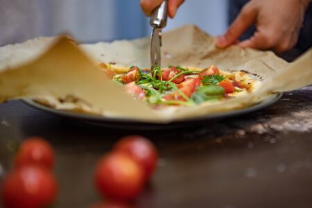 woman hand slicing pizza for pieces. close up