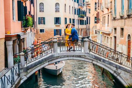 couple standing on the bridge crossing venice canals romantic city tourismの写真素材