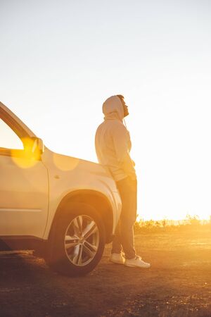 man enjoying freedom looking on sunset ar roadside. car travel concept. copy spaceの写真素材