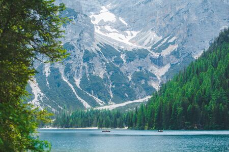 boats at the middle of braies lake in Italy. summer vacation. mirror reflection of mountains in waterの写真素材