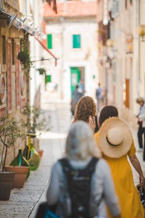 view from behind women walking by small porec city streets in croatia. vacation lifestyleの写真素材