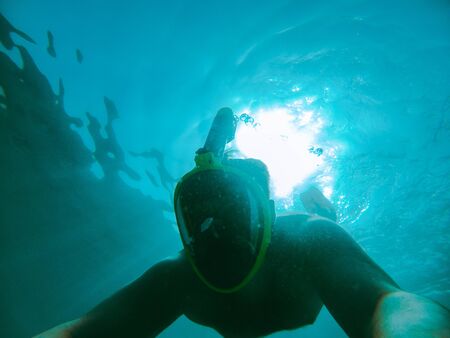 man swimming underwater with snorkeling musk summer sea vacation