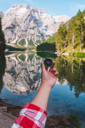 hand holding compass view of mountain lake on background. hiking concept