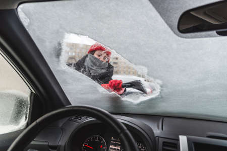 young pretty woman cleaning car after snow storm