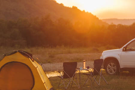 camping at beach of mountain river. suv car. yellow tent. camp table and chairs. copy spaceの写真素材