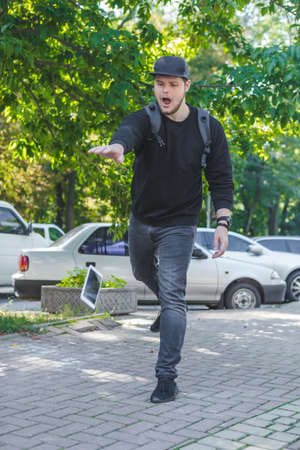 young man let down mobile phone on stone groundの写真素材