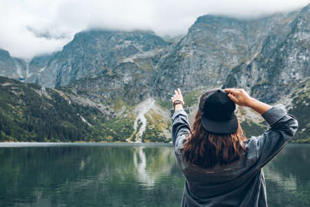woman trying reach out the sky landscape view of lake at mountains tatra national parkの写真素材
