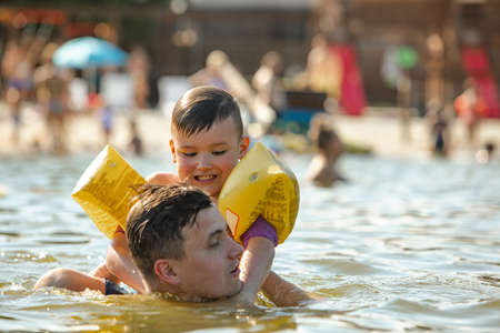 father throwing son in water having funの写真素材
