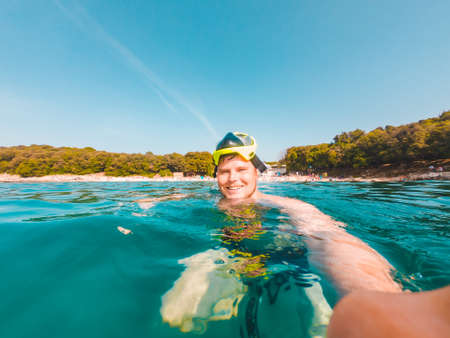 young smiling man taking selfie in snorkeling maskの写真素材