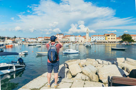 backpacker taking picture of town at sea beachの写真素材