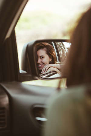 reflection on stunning smiling woman in car rear mirrorの写真素材