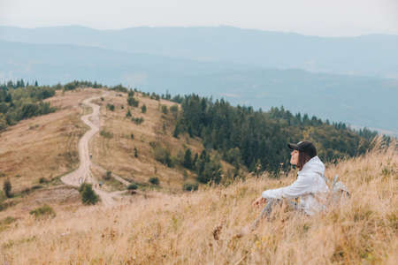 woman sitting on the ground looking at mountains hiking concept