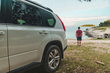 tourist man standing at sea beach suv car on frontの写真素材