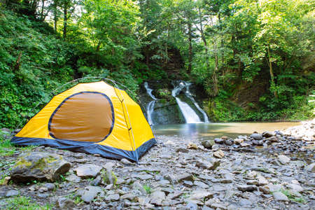 view of yellow hiking tent near waterfall. copy space. travel conceptの写真素材