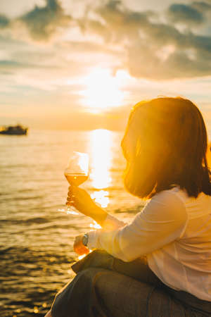 woman drink wine at sea beach looking on sunset. summer vacation.の写真素材