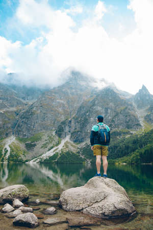 man with backpack looking at lake in mountains beautiful landscape