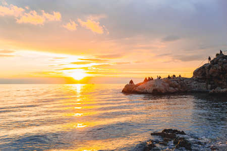 people resting at the beach of the sea enjoying view of sunset. copy spaceの写真素材