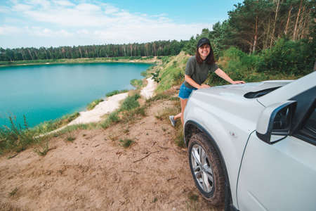 woman checking with map on the suv car hood lake with blue water on background copy space
