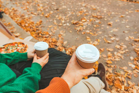 couple hands close-up holding mug with coffee to go. autumn warm dayの写真素材