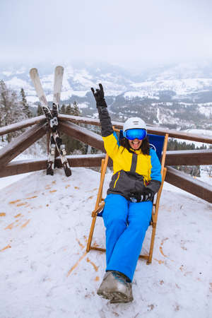 woman in ski outfit sitting on chair looking on panoramic view from the peak of the mountain copy spaceの写真素材