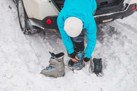 woman changing boots to ski close up near car trunk. winter activityの写真素材