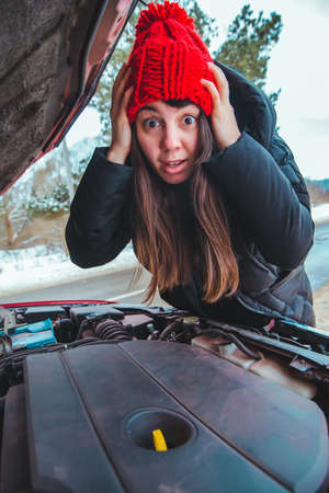woman looking at car engine road assistance concept winter seasonの写真素材