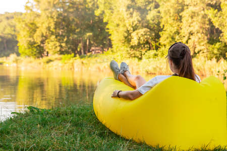 woman laying down relaxing on air sofa at lake beach warm autumn seasonの写真素材