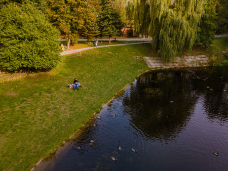 aerial view of couple laying down on blanket at the beach of public park lake autumn seasonの写真素材