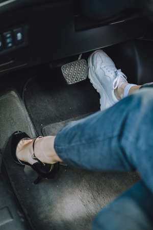 woman legs in high-heeled and sneakers shoes - choosing comfort for driving. copy spaceの写真素材