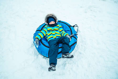 little kid in snow tube. winter time activitiesの写真素材